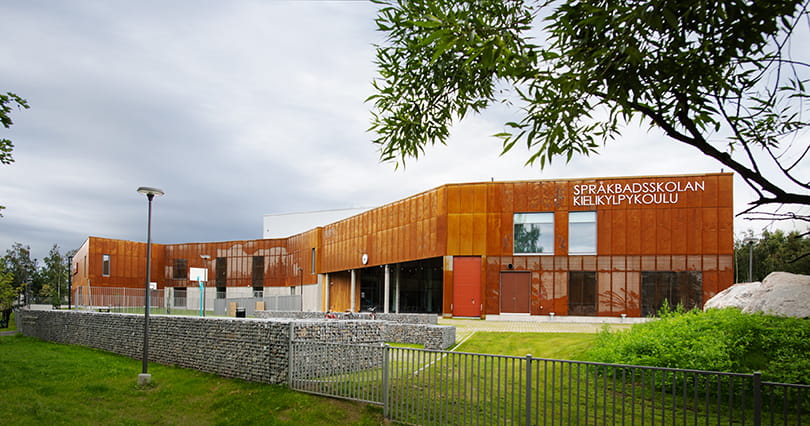 Språkbadeskolen har en moderne fasade i rustrødt.